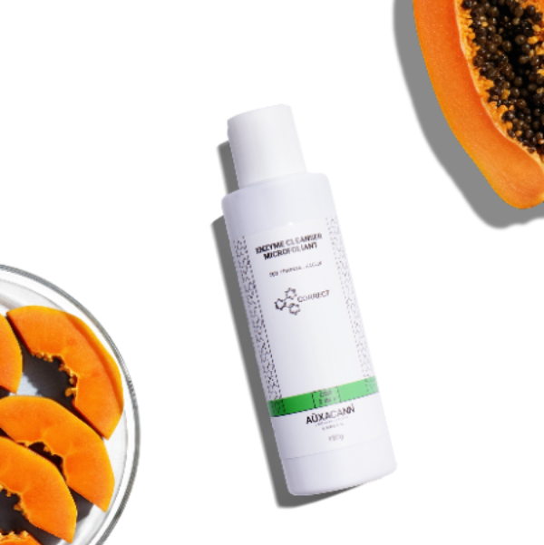 Skincare product bottle with sliced papaya on a white background